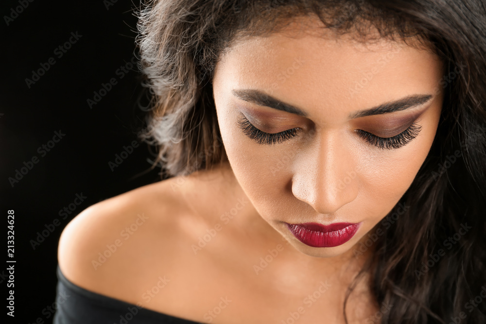 Attractive African-American woman with long eyelashes on black background. Eyelash extensions Attractive African-American woman with long eyelashes on black background. Eyelash extensions
