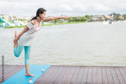 woman practicing yoga and meditation on mat near lagoon. sport and health concept  with copy space for text. © shutterdemon