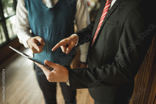 Two businessman standing and looking to tablet, they are talking about business plan, marketing and financial in the future. concept of business success.