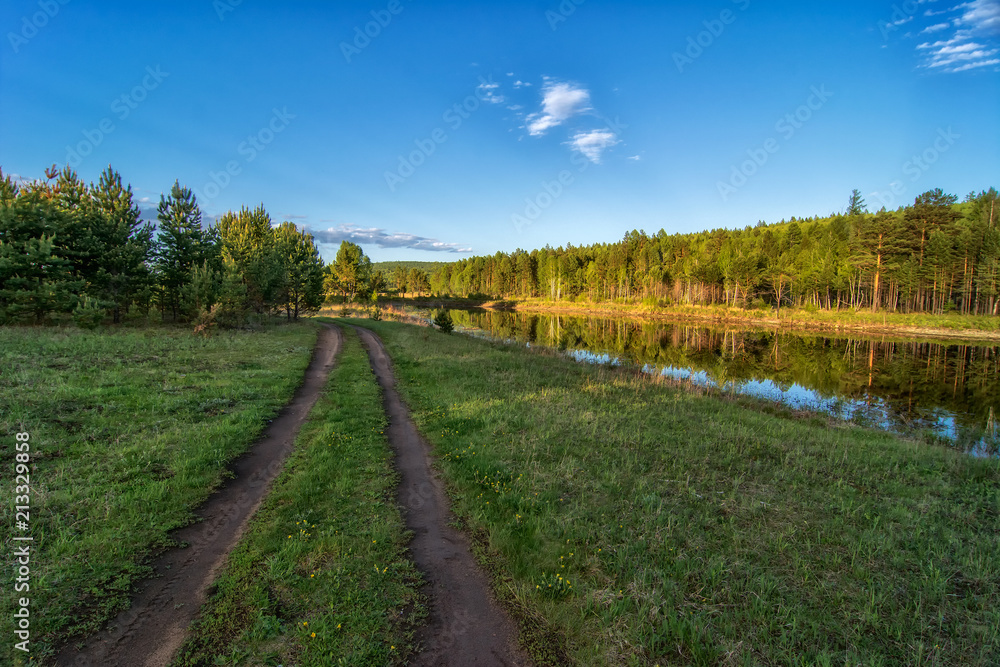 Road going near a forest lake in Siberia