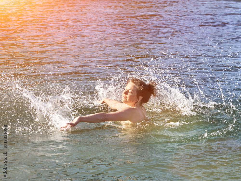 Young caucasian woman having fun and swimming in lake