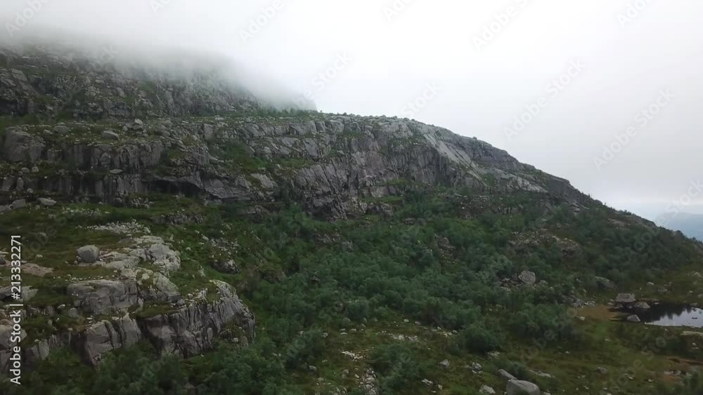Aerial shot of a mountain with trees under the clouds Aerial shot of a mountain with trees under the clouds