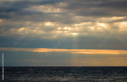 The rays of the sun make their way through the clouds  the seascape