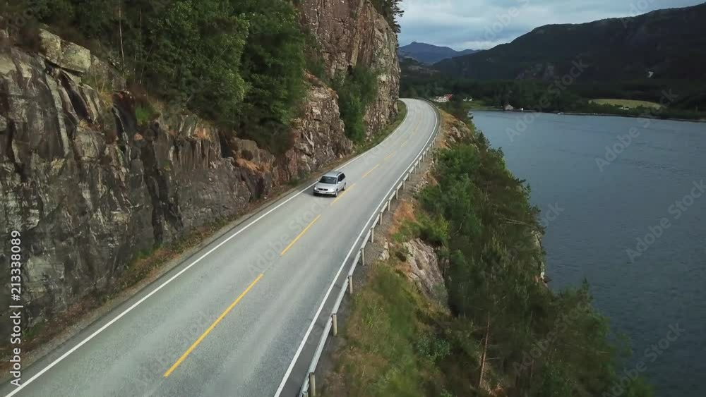 Aerial shot of a single car driving by the shoreline Aerial shot of a single car driving by the shoreline