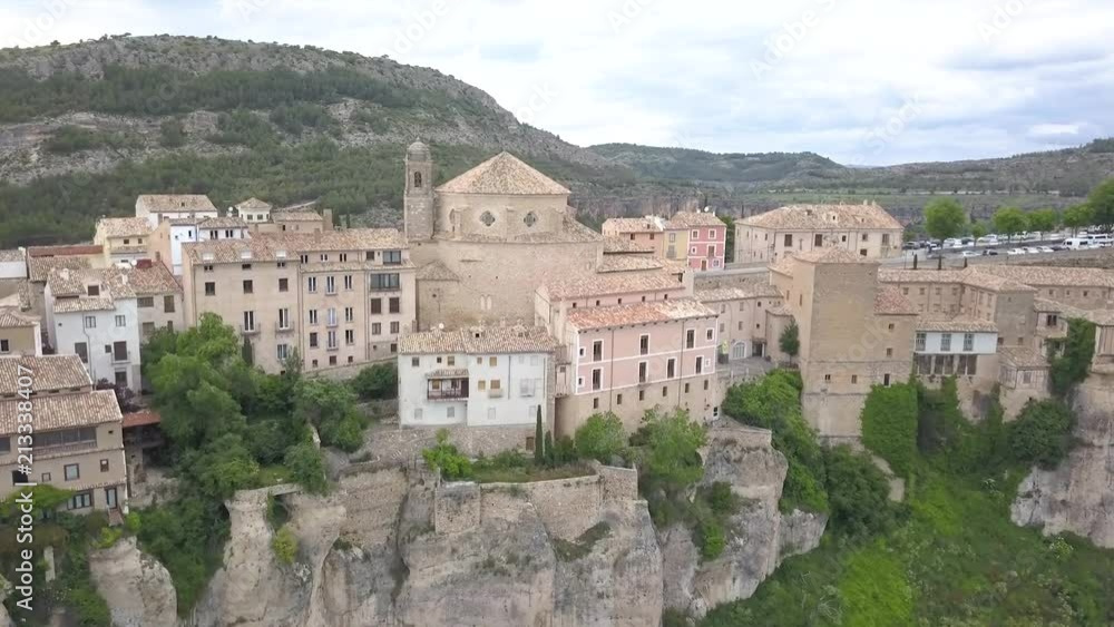Aerial view of Cuenca's historical cathedral which in on a cliff in the middle of a valley in Spain. Show are colorful pastel houses and other buildings. Aerial view of Cuenca's historical cathedral which in on a cliff in the middle of a valley in Spain. Show are colorful pastel houses and other buildings.