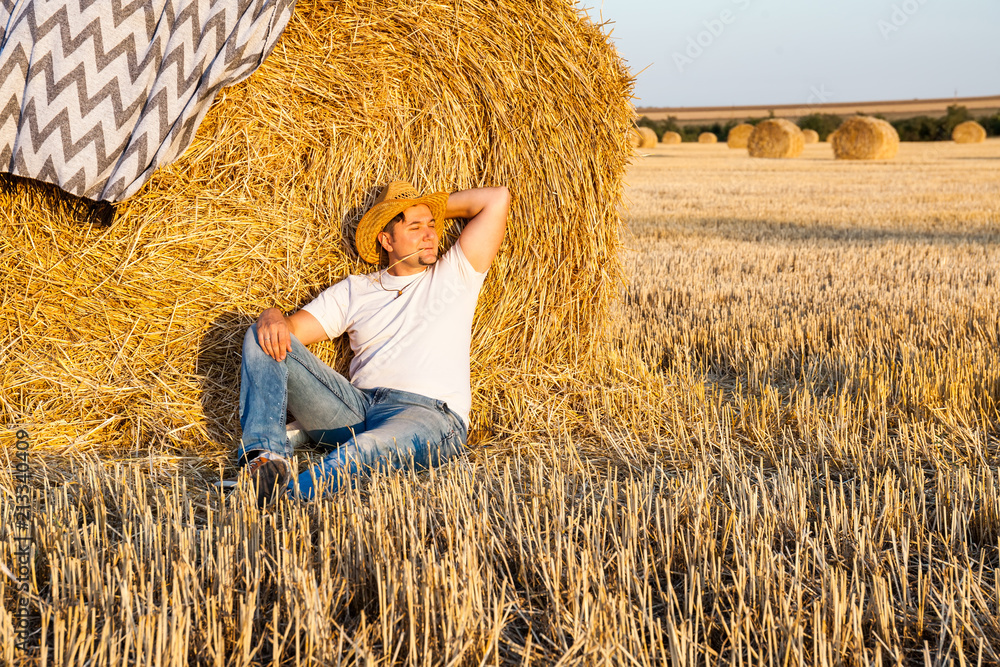 Cute man resting after hay harvesting in haystacks Cute man resting after hay harvesting in haystacks