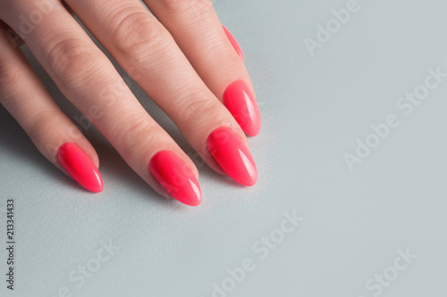 Women's hands with perfect red manicure. Nail Polish red coral color. blue background