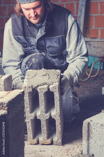 Real construction worker bricklaying the wall using tools.