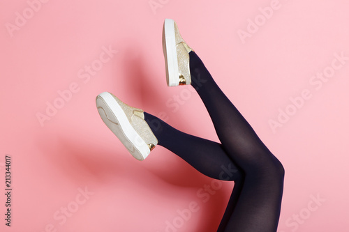 Legs of young caucasian woman in black tights and golden shoes