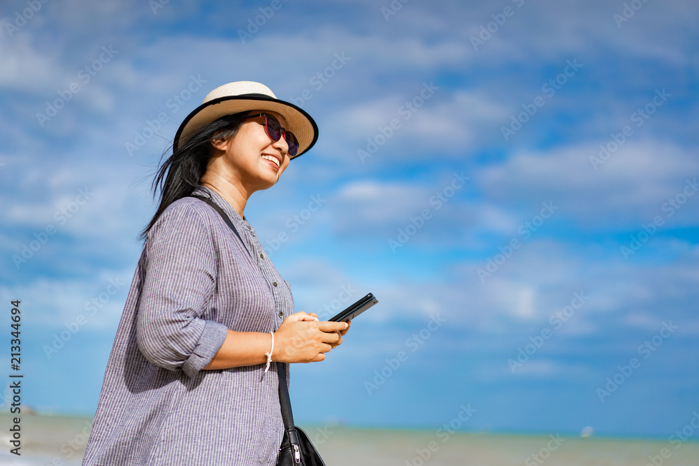 Traveller woman using smartphone on the beach