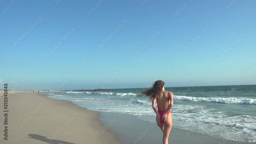 Vacation travel bikini woman walking on Los Angeles beach into water. Lady with slim sexy body on tropical white sand beach in going swimming in perfect turquoise ocean. Luxury destination. Vacation travel bikini woman walking on Los Angeles beach into water. Lady with slim sexy body on tropical white sand beach in going swimming in perfect turquoise ocean. Luxury destination.