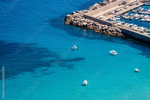 Aerial view of tropical turquoise blue sea with floating boats and people. High resolution image of sailing boats anchored next to reef around the coastline. Bird's eye view, ocean from above.