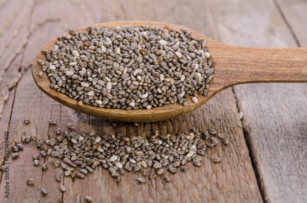 Chia seeds in wooden spoon over wooden table Chia seeds in wooden spoon over wooden table