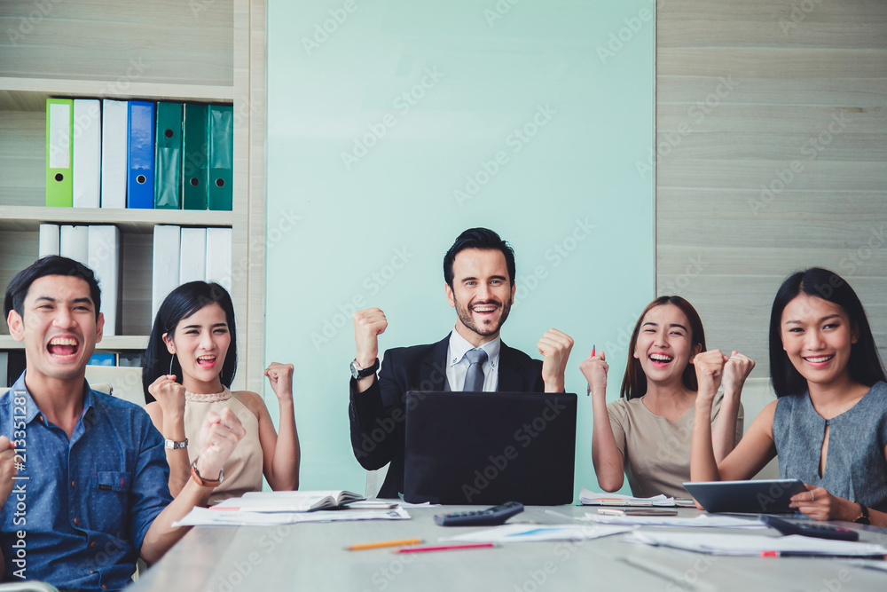 Fototapeta premium Happy Successful multiracial business team giving a high fives gesture as they laugh and cheer their success..