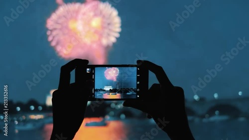 POV Closeup on the silhouette of a woman's hands taking photos of fireworks show with a mobile phone, shoot in 4K