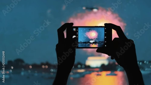POV Closeup on the silhouette of a woman's hands taking photos of fireworks show with a mobile phone, shoot in 4K