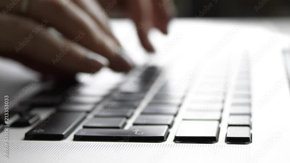 Fingers typing on a laptop, blue tone Fingers typing on a laptop, blue tone