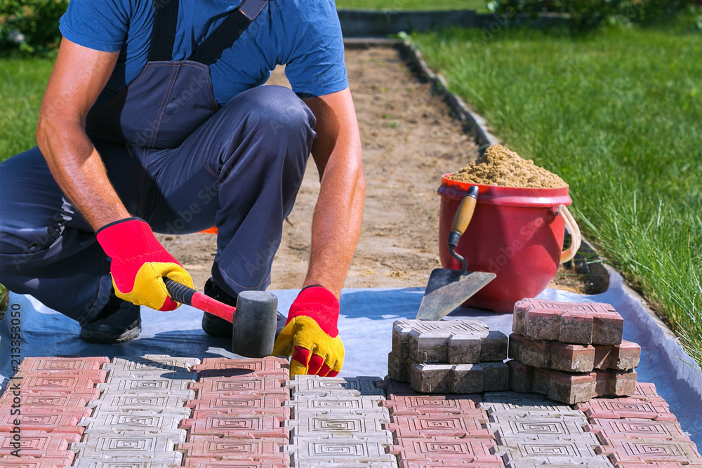 Laying of paving slabs in the garden.Man hitting the concrete slab with a  rubber hammer Stock Photo | Adobe Stock