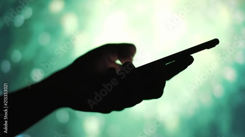 Closeup on the silhouette of a woman's hand sending a message on a mobile phone with fireworks in background, shoot in HD 1920p photo