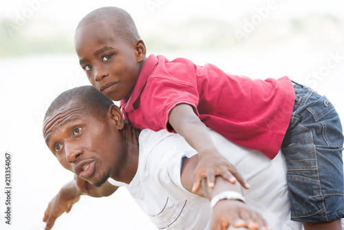 young father carrying his son smiling on his back