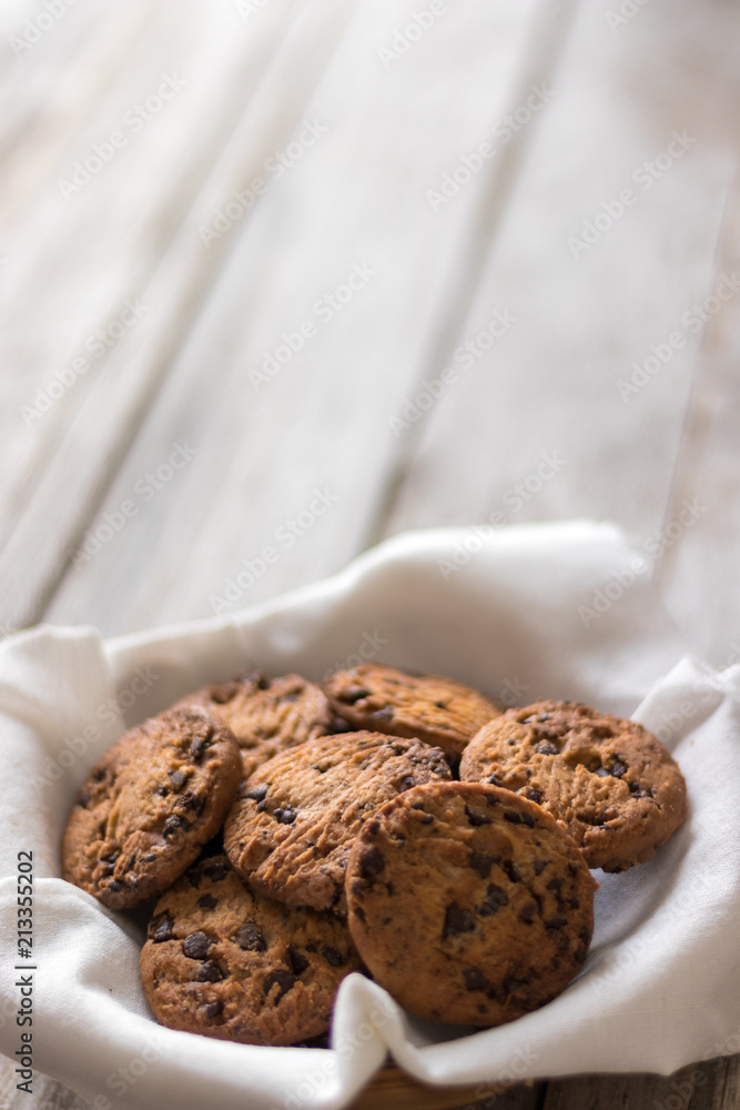Chocolate chips cookies in a basket on wooden background, homemade sweet and dessert concept