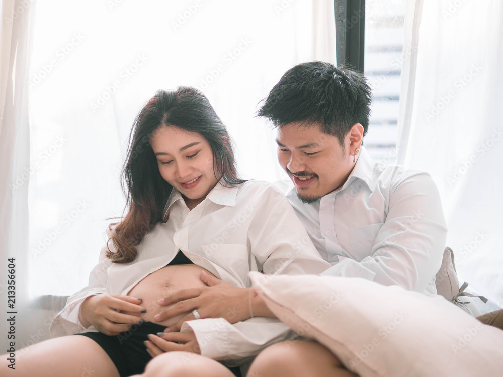 Asian man husband take care of his pregnant wife.Beautiful pregnant woman and her handsome husband are smiling while spending time together. Asian man husband take care of his pregnant wife.Beautiful pregnant woman and her handsome husband are smiling while spending time together.