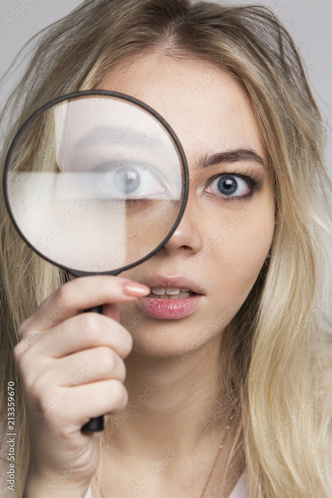 Young woman looking through a magnifying glass Young woman looking through a magnifying glass