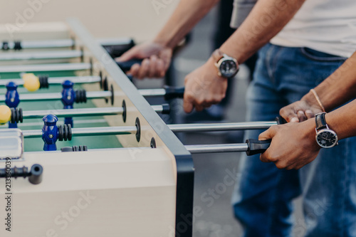 Table football game or soccer. Men play kricker together during weekend as have spare time, enjoy recreation time. Heated people.