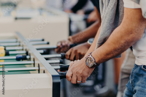 Table football kicker. Best friends enjoy togetherness, recreat in entertainment place, play table soccer together, have free time. People and rest concept photo