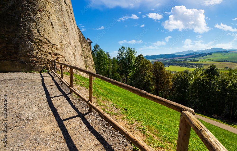 castle wall and railing on a hill. view in to the beautiful mountainous landscape 