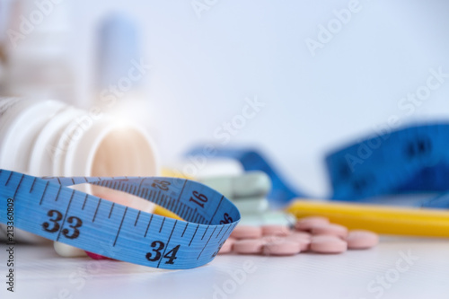 Slim concept: Blurred picture of pills, dangerous for health, close up of tape for measure the body size