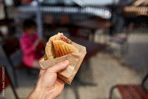 First person view shot of a man eating hamburger in the street cafe, soft focus, shallow depth of field. photo