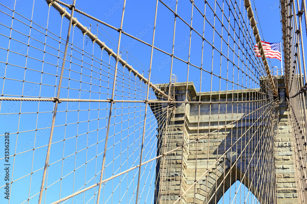 Naklejka premium Zbliżenie na Brooklyn Bridge i American Flag nad East River, Nowy Jork, USA