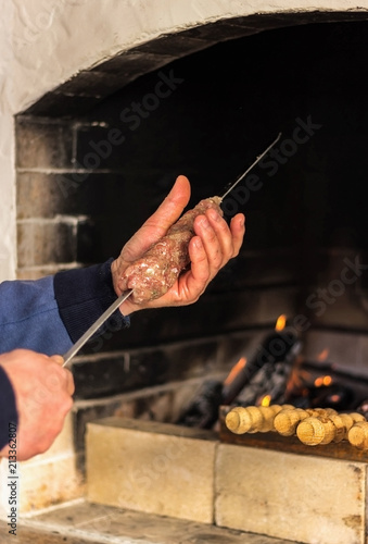 Man string a meat on a skewer to cooking a very delicious kebab. Summer day. Family dinner.