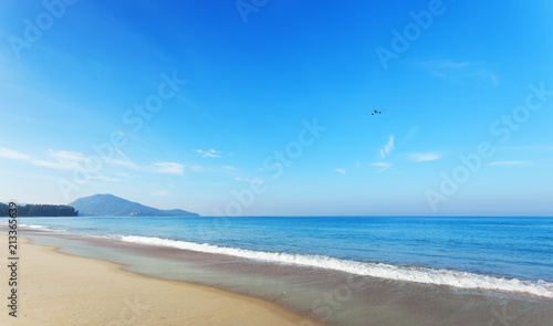 Tropical andaman seascape scenic off mai khao beach and wave crashing on sandy shore in phuket thailand with airplane takes off on sky in summer season.