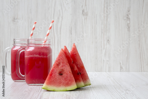 Skices of watermelon with smoothie in glass jars on a white wooden background, side view. Copy space.