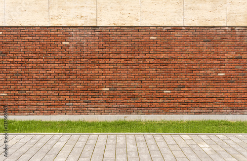 The wall of the house is red brick. The lawn in front of the house. Street and sidewalk.