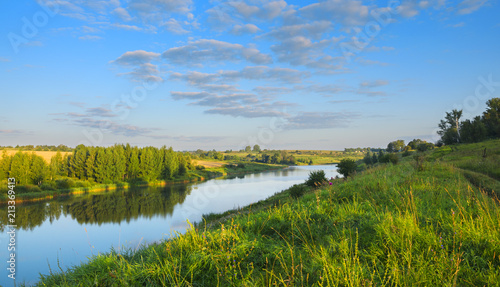 Tranquil summer landscape with beautiful river,woods,fields and green hills.Sunny windless morning.