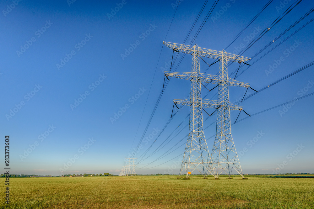 High voltage pylons against a blue sky in dramatized colors