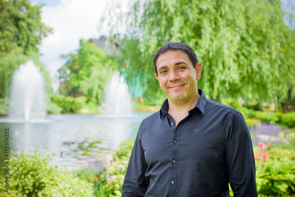 Middle age arabic smiling man in black shirt at park with good mood Middle age arabic smiling man in black shirt at park with good mood