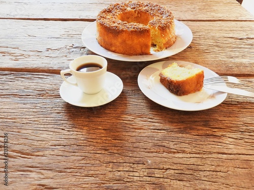 Round cake, coffee cup and plates on rustic wooden table.