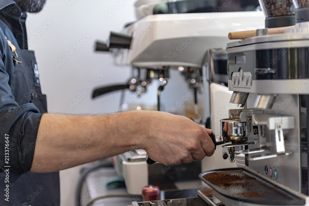 Ein Barista bereitet an einer Siebträger Kaffeemaschine einen Espresso oder Cappuccino zu  