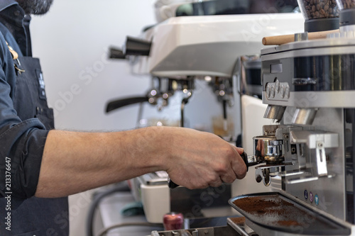 Ein Barista bereitet an einer Siebträger Kaffeemaschine einen Espresso oder Cappuccino zu 