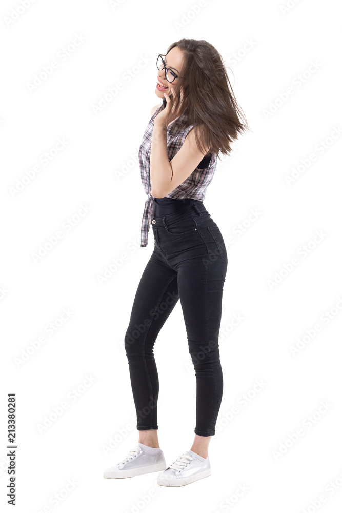 Side view of beautiful young hipster style woman talking on the phone laughing and looking away. Full body isolated on white background. Side view of beautiful young hipster style woman talking on the phone laughing and looking away. Full body isolated on white background.