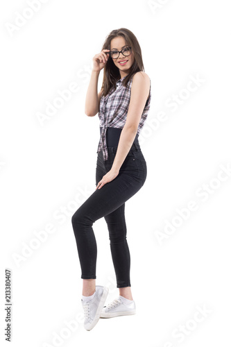 Side view of young sexy hipster woman holding eyeglasses and posing at camera. Full body isolated on white background. 