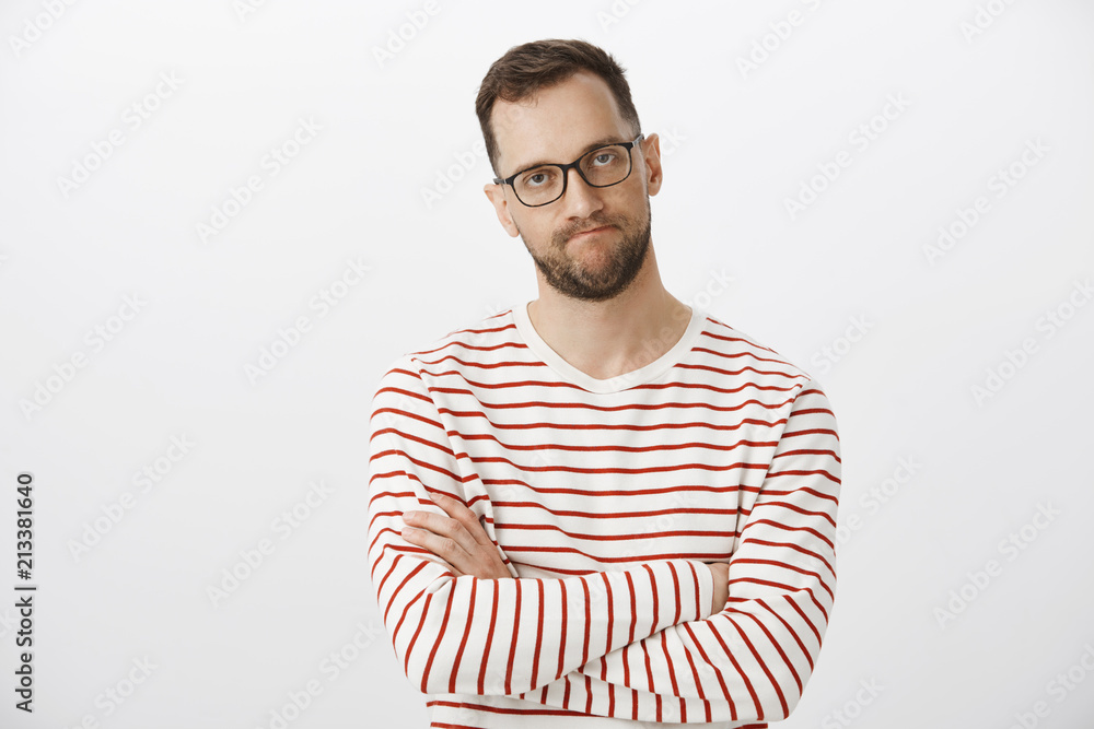 Waist-up shot of intense pissed off european entrepreneur in black glasses, crossing hands on chest and clenching lips, looking at annoying person, being outraged and trying control emotions Waist-up shot of intense pissed off european entrepreneur in black glasses, crossing hands on chest and clenching lips, looking at annoying person, being outraged and trying control emotions