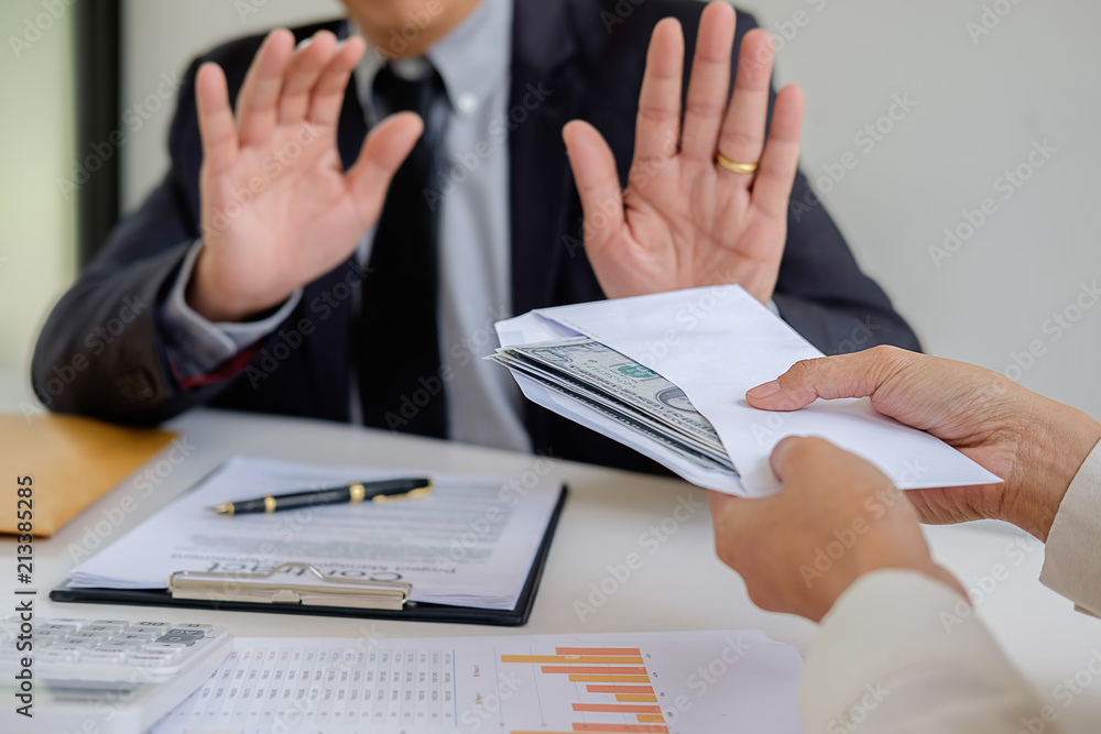 Businessman refusing money in the envelope to agreement contract, Bribe and corruption concept Businessman refusing money in the envelope to agreement contract, Bribe and corruption concept