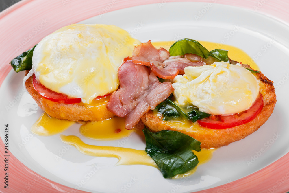 English breakfast- Fried bread toast with egg, spinach, tomatoes, mozzarella cheese and ham on plate on dark wooden background