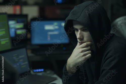 Cool hacker with hoodie working with computers © stokkete