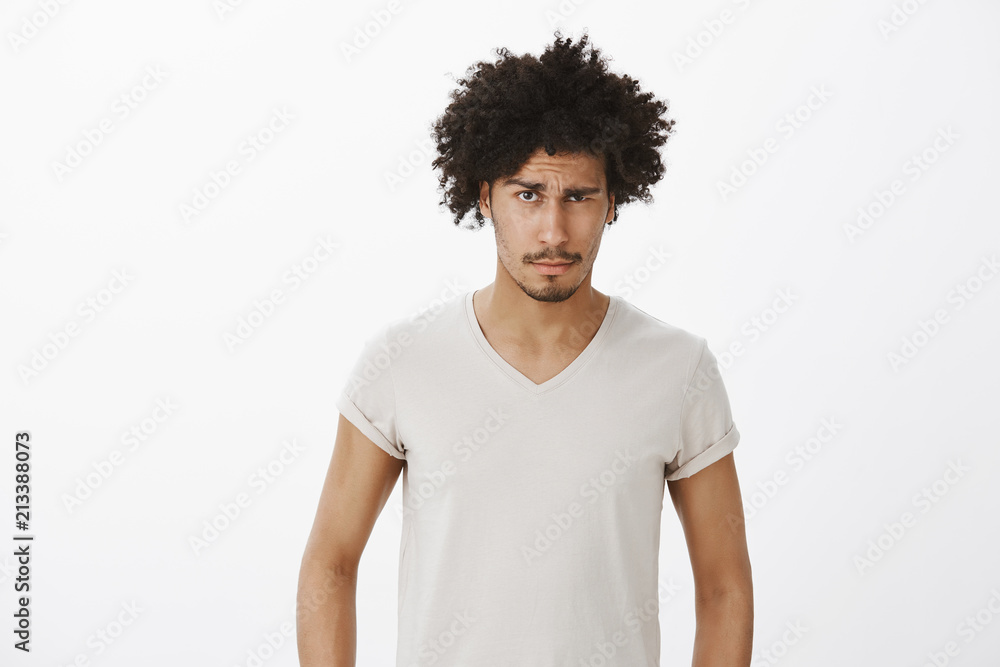 Studio shot of confused intense good-looking male with tanned skin and moustache, raising eyebrow suspiciously and gazing doubtful at camera, being questioned and unsure over gray background Studio shot of confused intense good-looking male with tanned skin and moustache, raising eyebrow suspiciously and gazing doubtful at camera, being questioned and unsure over gray background